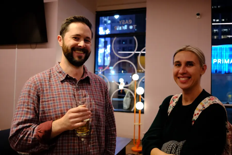 Two attendees smiling with drinks