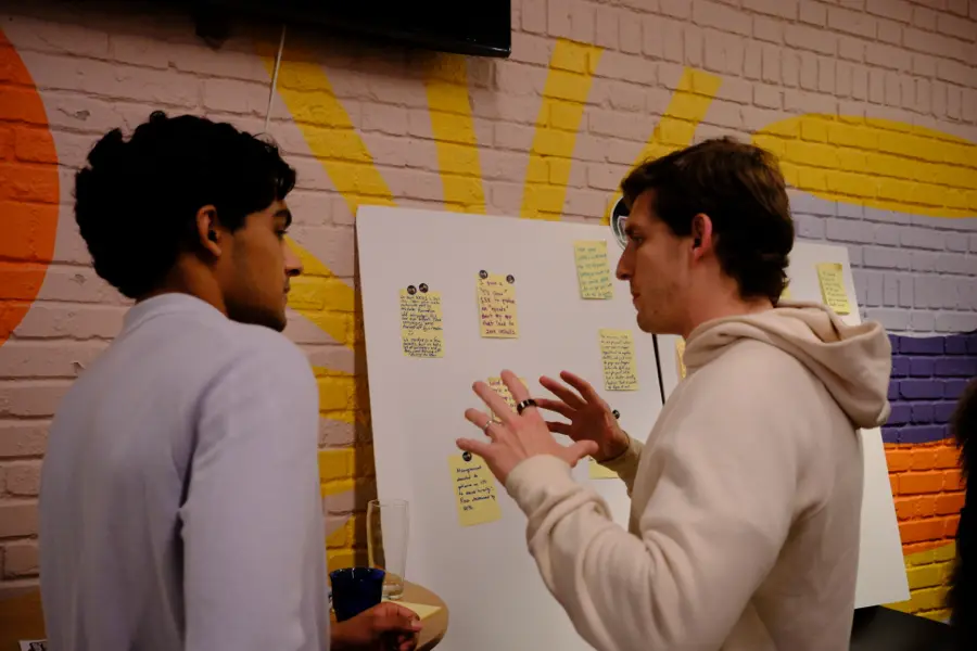 Two attendees discussing the Screw-Ups board