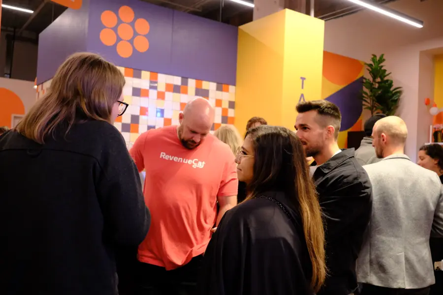 An attendee in a RevenueCat shirt talking with guests